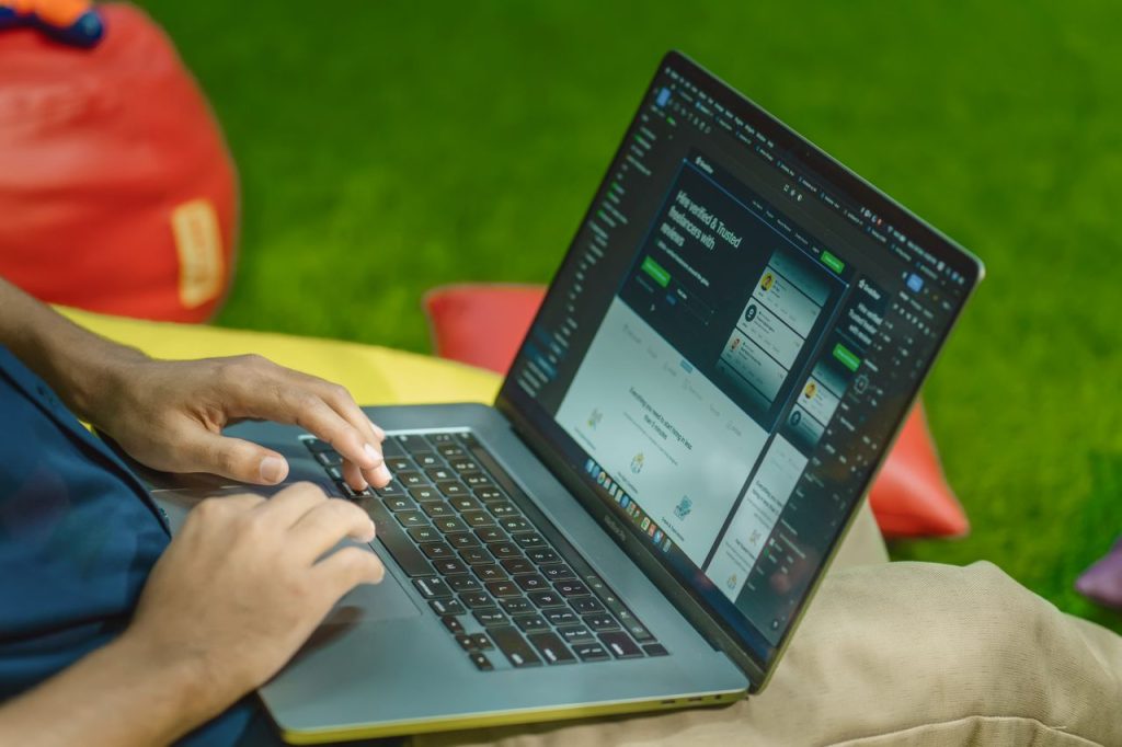 A person using a laptop outdoors on a sunny day, showcasing digital nomad lifestyle.